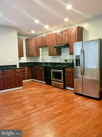 a large kitchen with stainless steel appliances granite countertop a stove a sink and a refrigerator