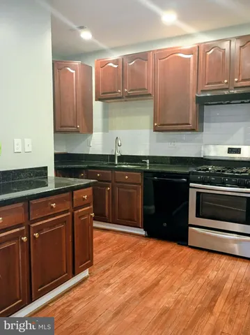 a kitchen with stainless steel appliances granite countertop a stove a sink and white cabinets
