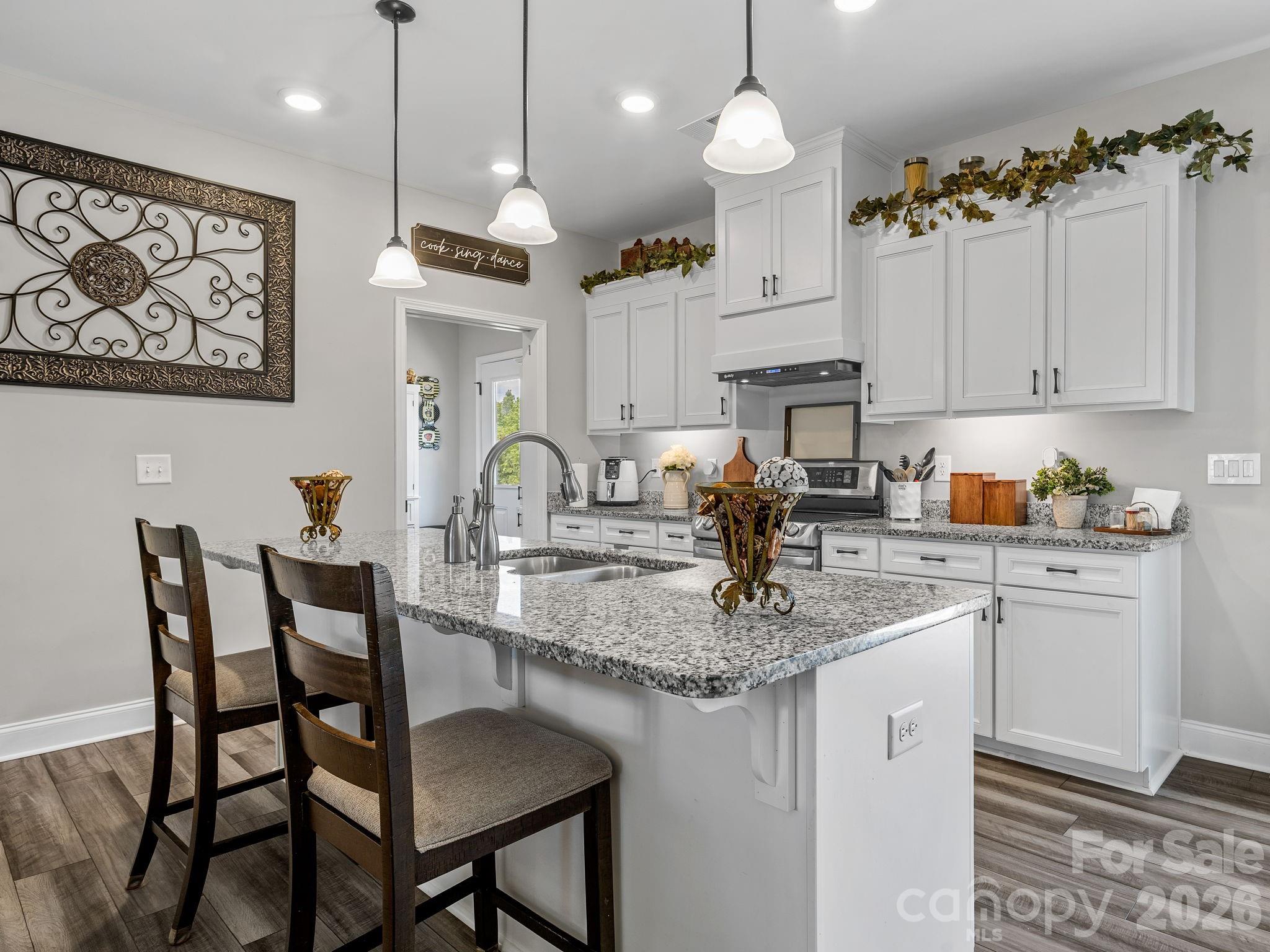 1076 McSwain Road Chesnee, SC 29323 - Photo 11 of 36 a kitchen with stainless steel appliances granite countertop a sink a refrigerator a stove a dining table and chairs with wooden floor