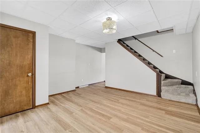 a view of an empty room with wooden floor and stairs
