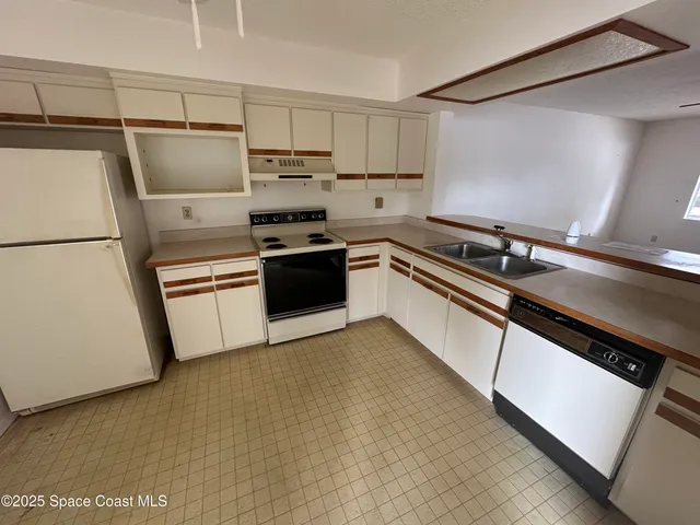 a kitchen with granite countertop a refrigerator sink stove and white cabinets