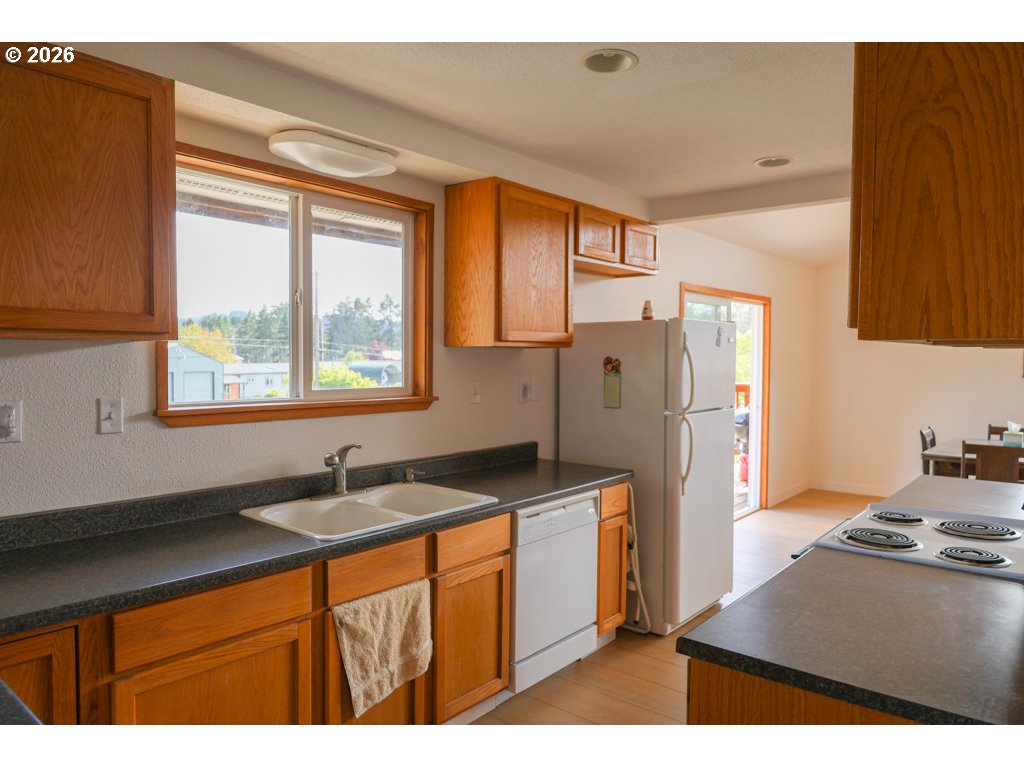 610 Tiara Street Lakeside, OR 97449 - Photo 10 of 28 a kitchen with stainless steel appliances granite countertop a refrigerator a sink and a stove