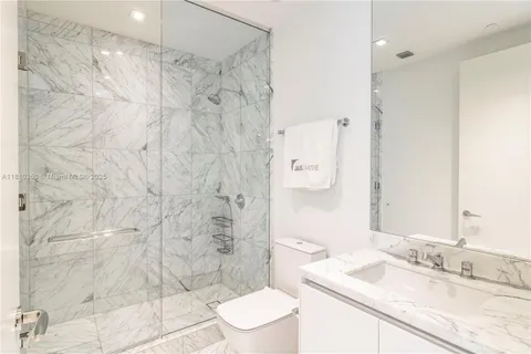 a bathroom with a granite countertop sink a toilet a mirror and shower