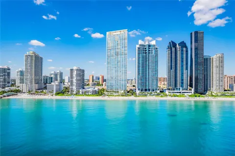 a view of a swimming pool with lawn chairs and a large tree
