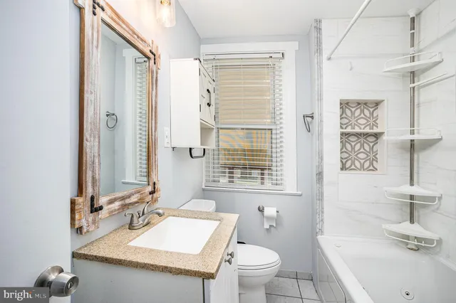a bathroom with a granite countertop sink toilet a mirror and shower
