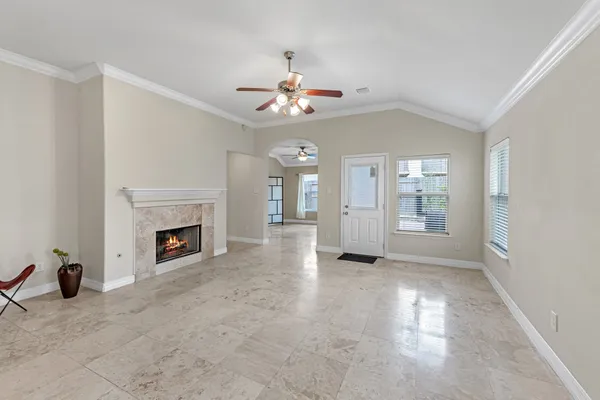 a view of a livingroom with a fireplace a chandelier fan and windows