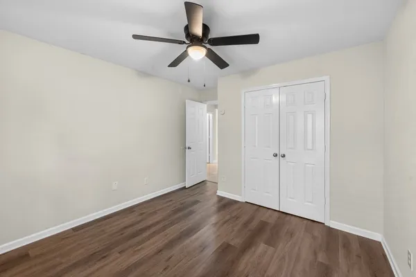 a view of a room with wooden floor closet and ceiling fan