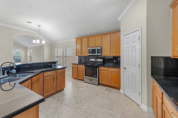 a large kitchen with stainless steel appliances granite countertop a stove a sink and a refrigerator
