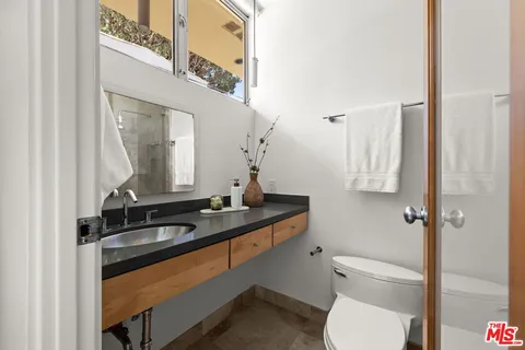a bathroom with a granite countertop toilet sink and mirror