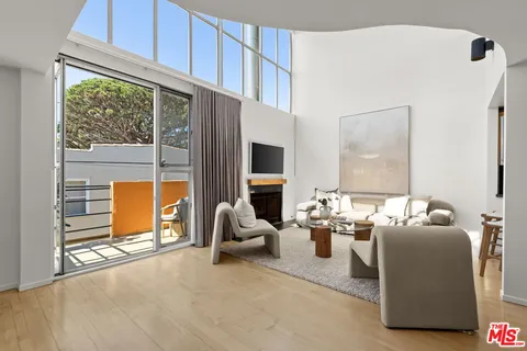 a living room with furniture a flat screen tv and floor to ceiling window