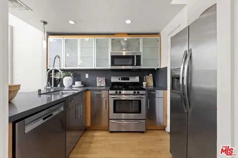 a kitchen with stainless steel appliances granite countertop a refrigerator a stove and a sink