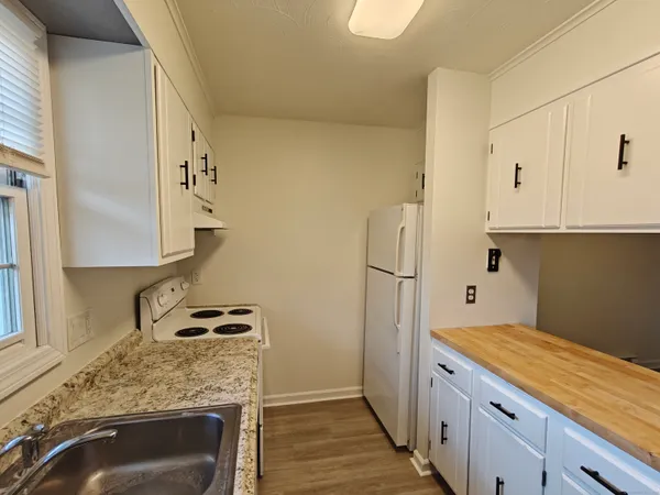 a kitchen with granite countertop white cabinets and refrigerator