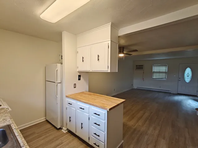 a kitchen with white cabinets and wooden floor