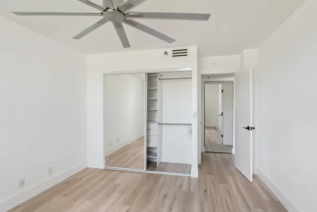 a view of empty room with wooden floor and ceiling fan