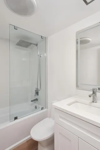 a bathroom with a granite countertop bathtub shower sink vanity and toilet