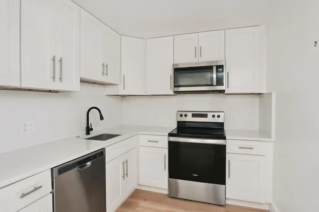 a kitchen with granite countertop white cabinets and stainless steel appliances