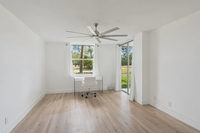 an empty room with windows and a ceiling fan