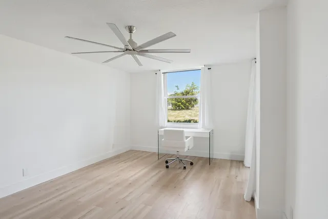 an empty room with a window and a ceiling fan
