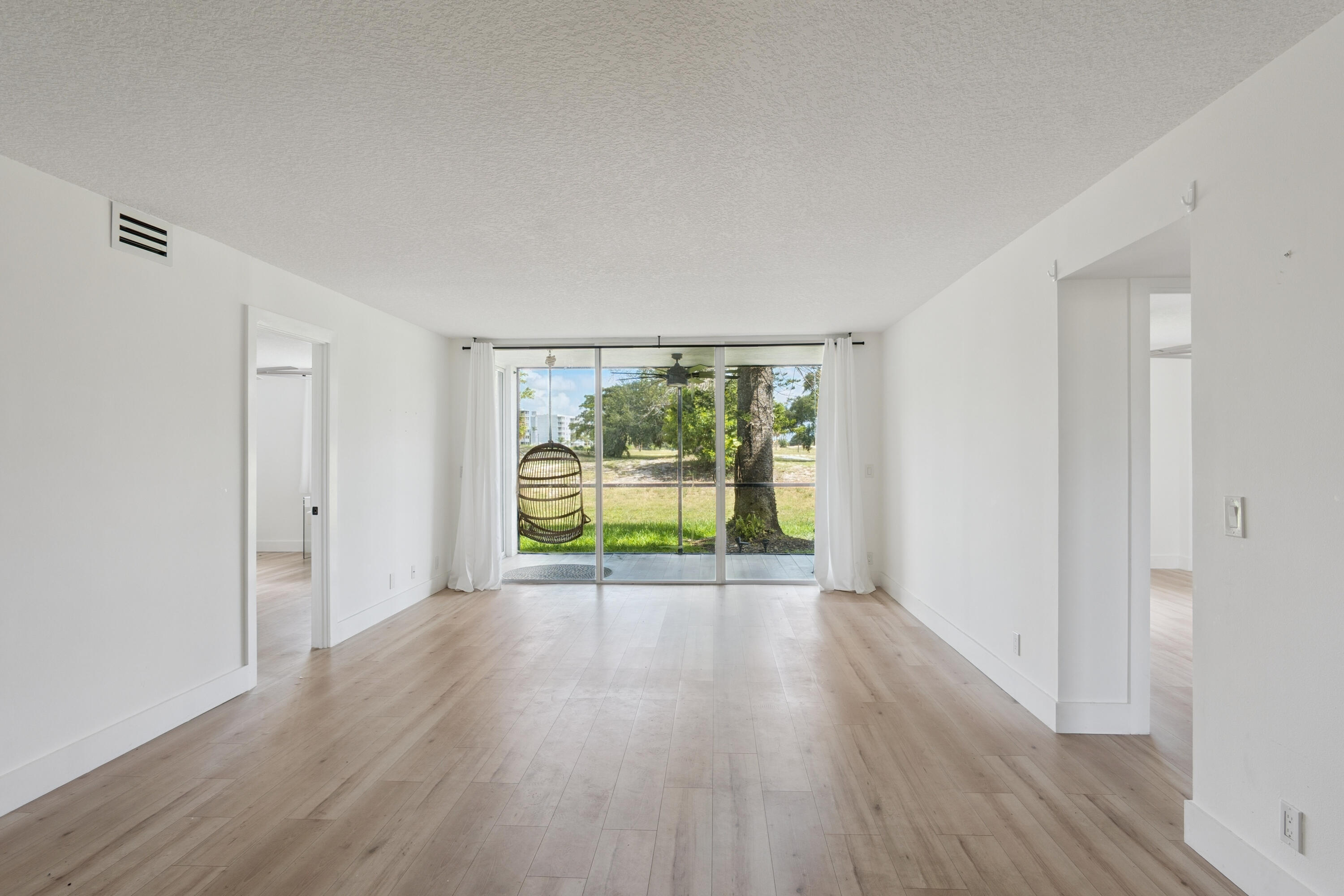 5260 Northwest 2nd Avenue, Unit 105 Boca Raton, FL 33487 - Photo 7 of 24 a view of an empty room with wooden floor and a window