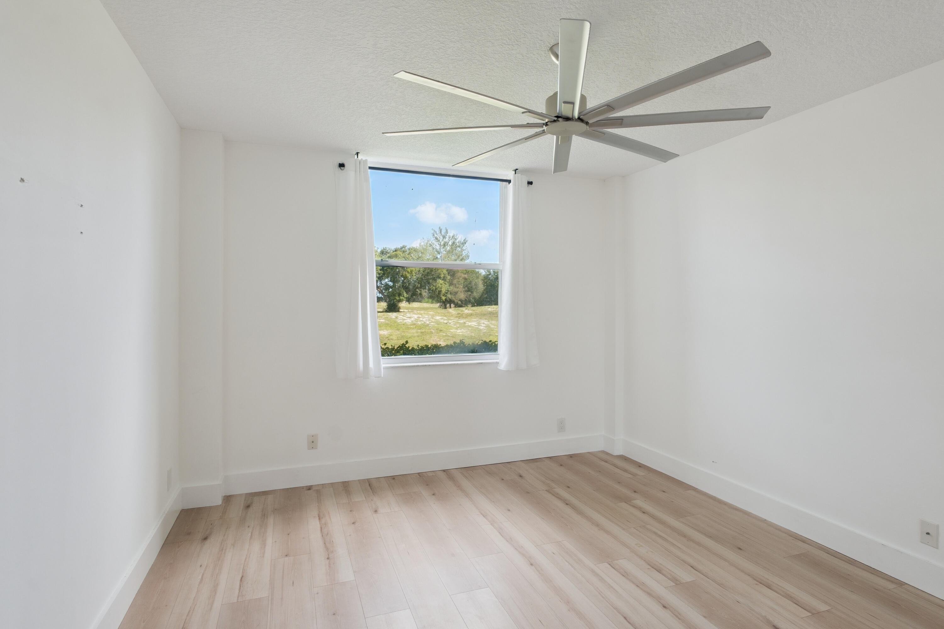 5260 Northwest 2nd Avenue, Unit 105 Boca Raton, FL 33487 - Photo 10 of 24 an empty room with a window and wooden floor