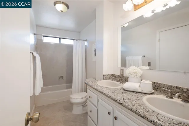 a bathroom with a granite countertop sink a toilet a mirror and shower