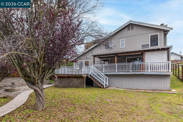 a front view of a house with a yard balcony and large tree