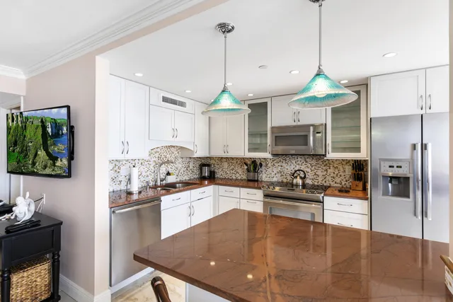 a kitchen with stainless steel appliances granite countertop a sink a stove a refrigerator and a center island