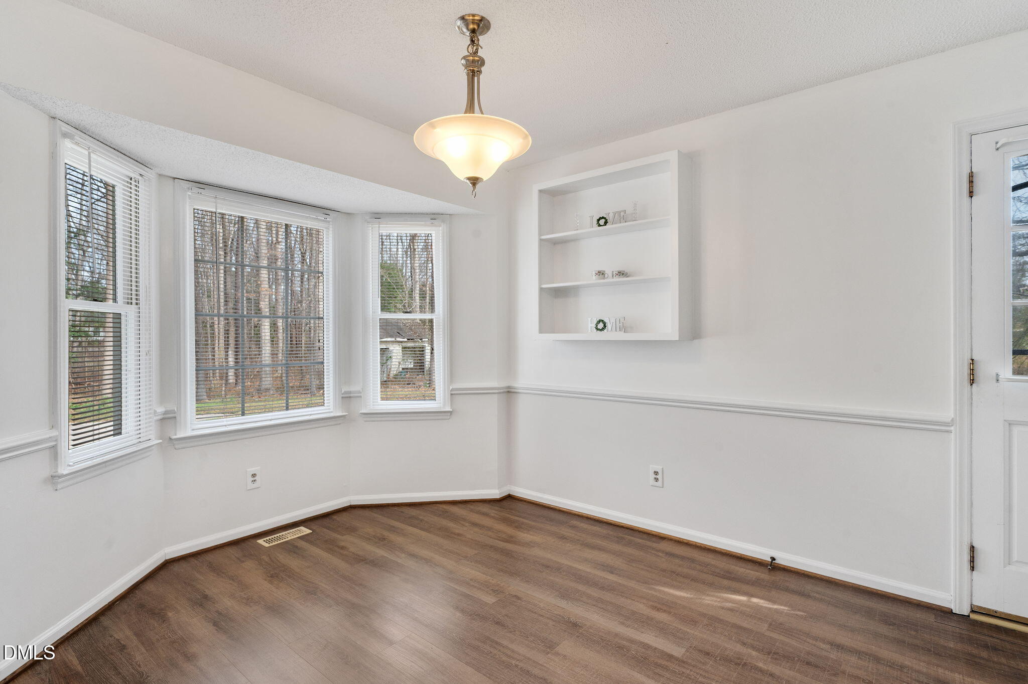 9205 Tree Meadow Lane Raleigh, NC 27603 - Photo 13 of 44 a view of an empty room with a window and wooden floor