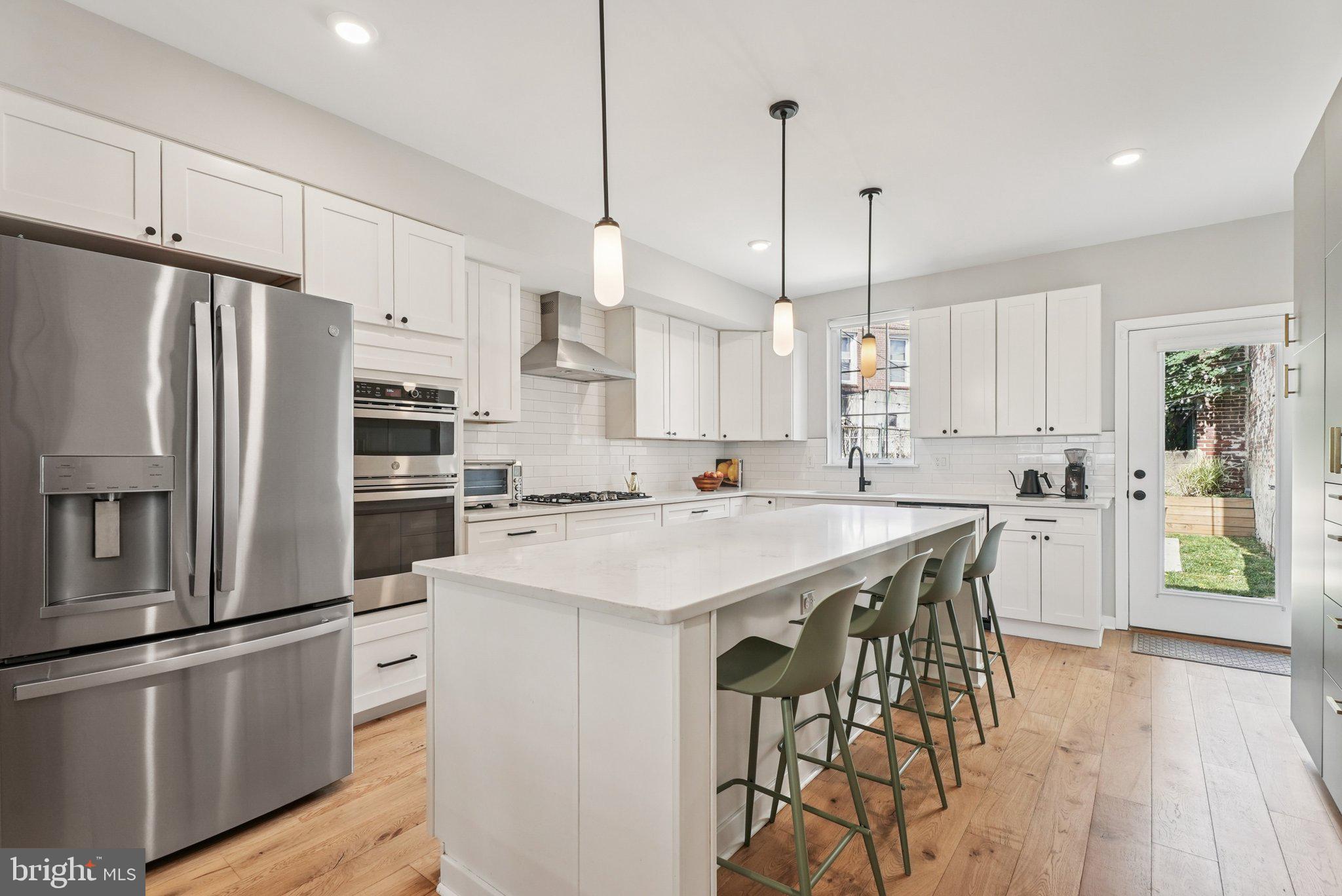 919 Reed Street Philadelphia, PA 19147 - Photo 9 of 28 a kitchen with stainless steel appliances kitchen island a table chairs refrigerator and microwave