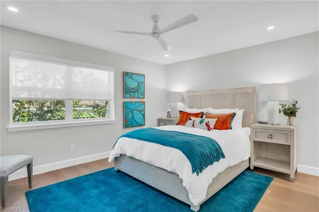 a bedroom with a bed lamp and a large window with wooden floor