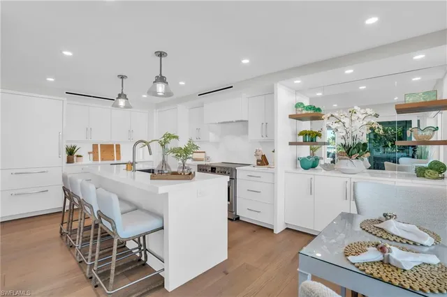 a kitchen with stainless steel appliances kitchen island granite countertop a table chairs in it and wooden floor