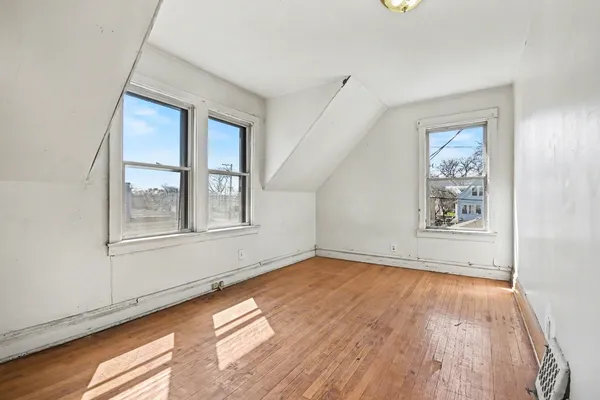a view of an empty room with window and wooden floor