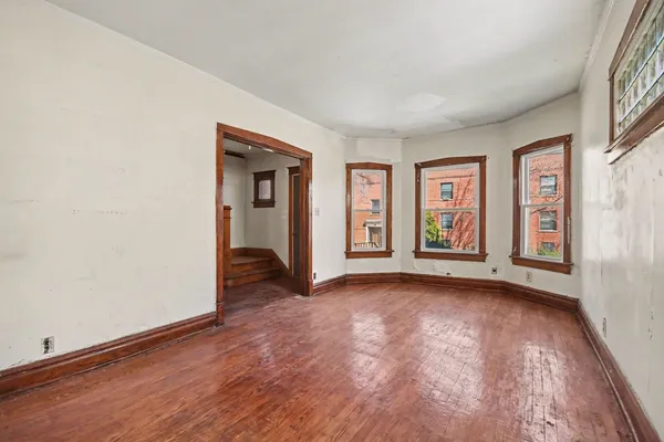 a view of an empty room with glass door and wooden floor