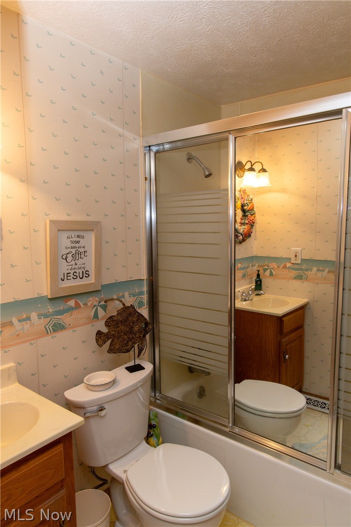 5467 Chapel Road Madison, OH 44057 - Photo 14 of 50 Full bathroom featuring a white bathtub with sliding glass doors, a single vanity with wood-finish cabinetry, a white toilet, and patterned wall panels