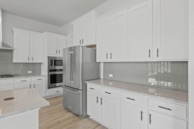 a kitchen with granite countertop white cabinets and stainless steel appliances