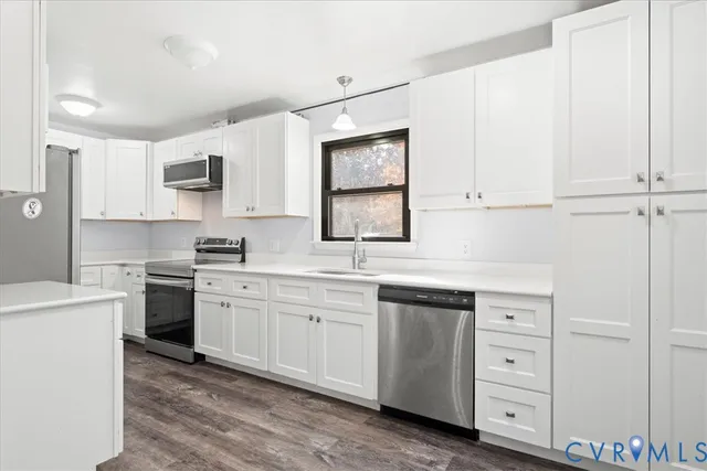 a kitchen with a sink stove cabinets and wooden floor