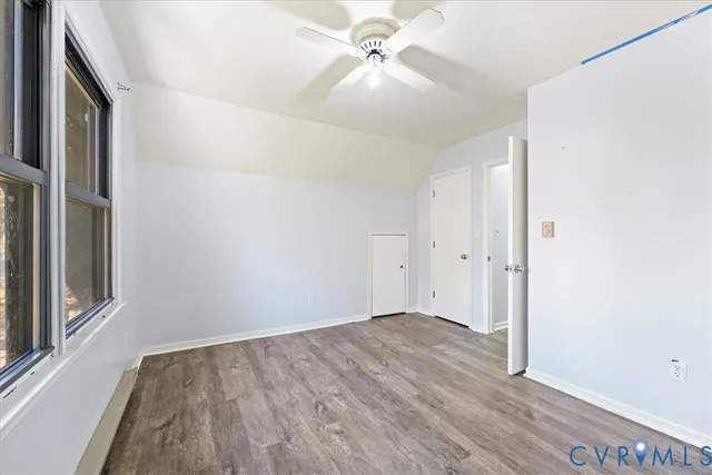 an empty room with wooden floor chandelier fan and windows