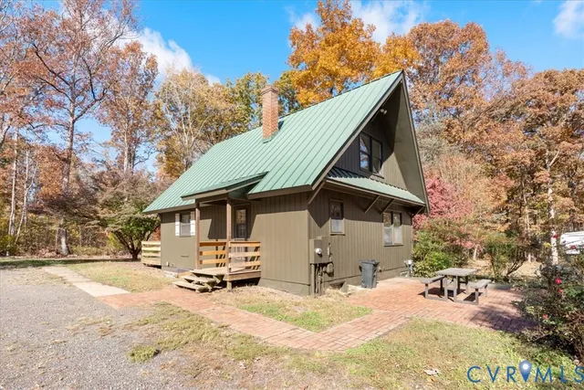 a backyard of a house with table and chairs under an umbrella