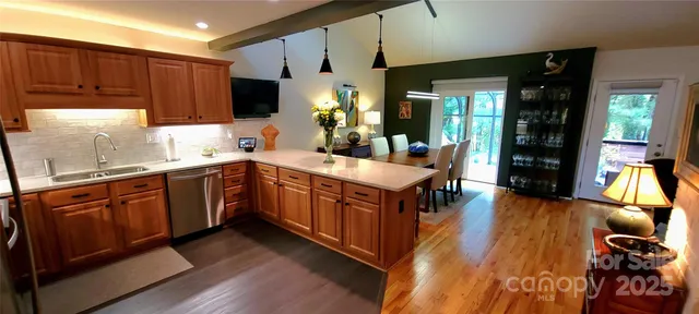 a kitchen with stainless steel appliances granite countertop a refrigerator a sink dishwasher and wooden cabinets with wooden floor