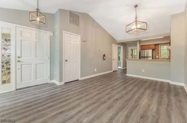 a view of an empty room with wooden floor and windows