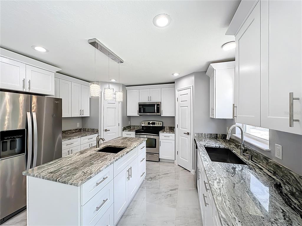 11963 Bentry Street Orlando, FL 32824 - Photo 24 of 80 a kitchen with stainless steel appliances granite countertop a sink stove microwave and refrigerator