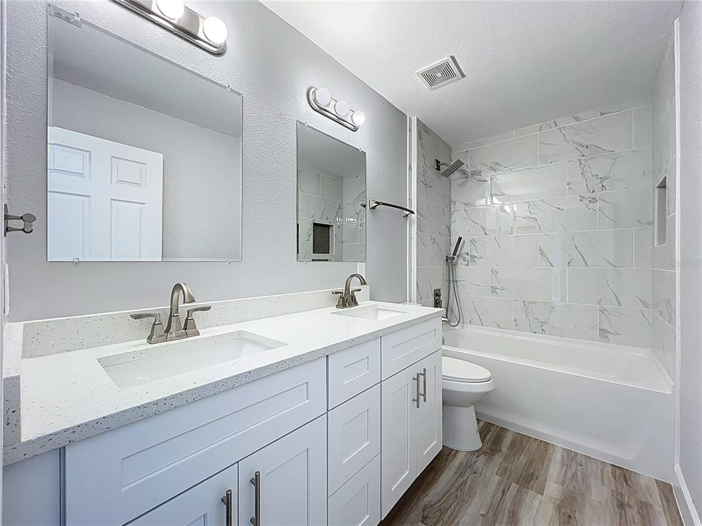 11963 Bentry Street Orlando, FL 32824 - Photo 45 of 80 a bathroom with a double vanity sink toilet mirror and bathtub