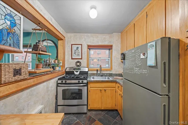 a kitchen with stainless steel appliances granite countertop a refrigerator a stove and a sink with wooden floor