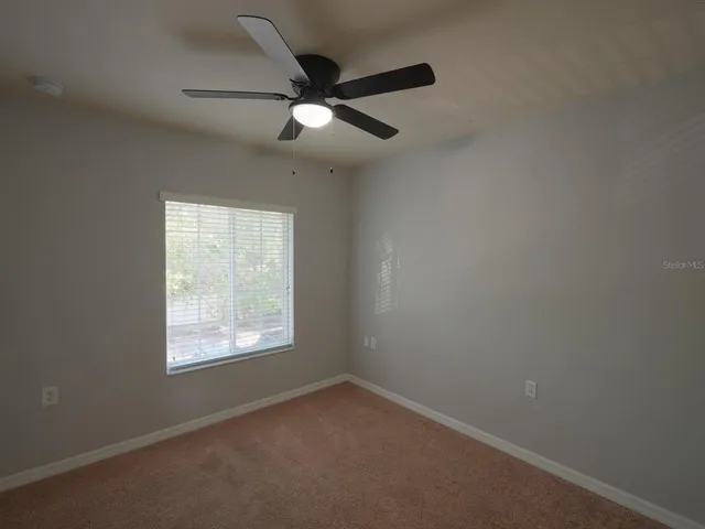 an empty room with a window and a fan