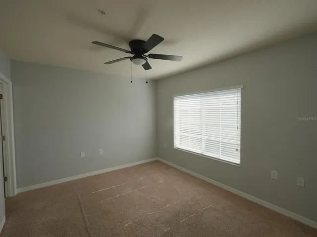an empty room with a window and a fan