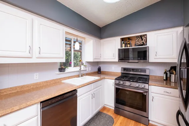 a kitchen with granite countertop a sink cabinets and stainless steel appliances