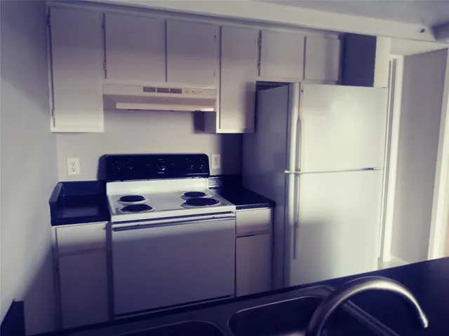 a kitchen with cabinets and a refrigerator