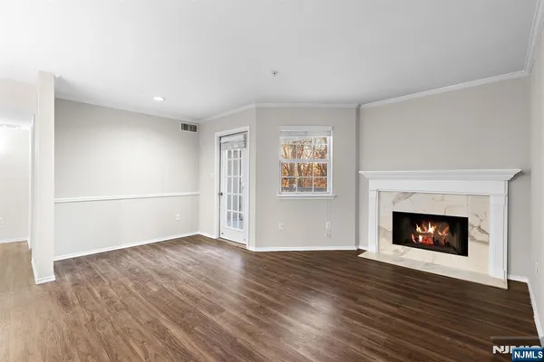 a view of an empty room with wooden floor fireplace and a window