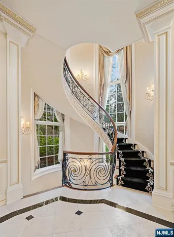 a spacious bedroom with a bed a chandelier and a mirror on the dresser