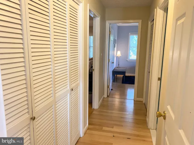 a view of a hallway with wooden floor and a bathroom